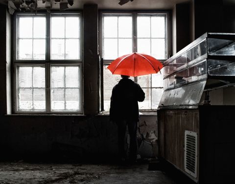 Човек държи червен чадър отворен вътре в сградата