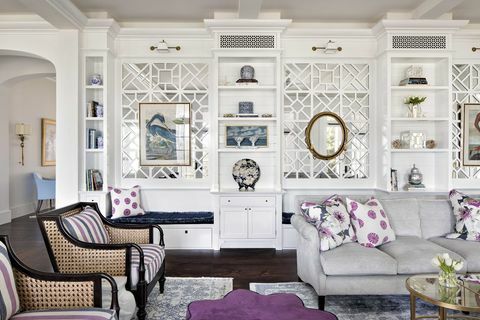 всекидневна, сив диван, лилави и бели декоративни възглавници, бели шкафове за съхранение, лилава тахта