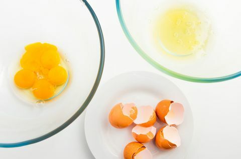 Яйчен жълтък и яйчен белтък в отделна стъклена купа. Яйце и яйце на бяла чиния.