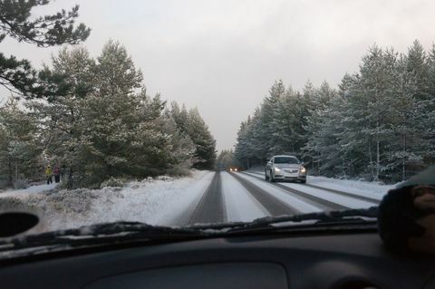 Кола кара по път, покрит със сняг сред дървета