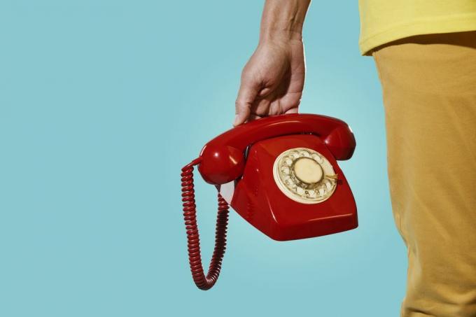 мъж със стар червен телефон в ръка