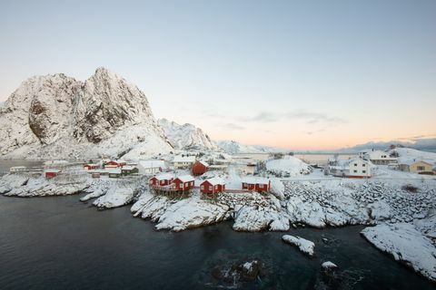 Село червена рибарска къща сред снега с гледка към планината в остров Lofoten Hamnoy Норвегия