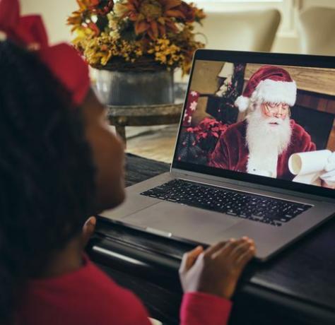 малко момиченце, говорещо с Дядо Коледа по компютърна видеоконференция