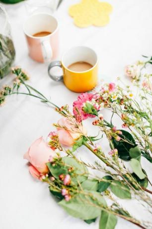 Маса с нарязани цветя и чаши за кафе в ателието за подреждане на цветя
