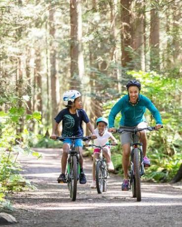 жена и двете й деца карат колело в гората на слънце