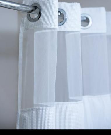 бяла завеса за душ, окачена на хромирана пръчка за завеси за душ
