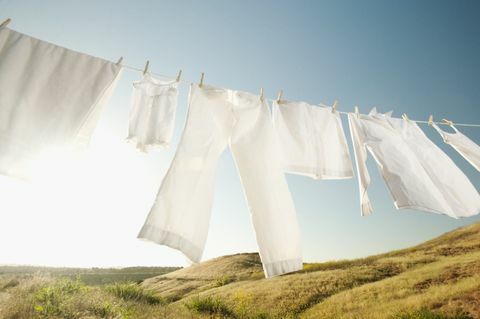Чисти бели дрехи, висящи на външната линия за пране