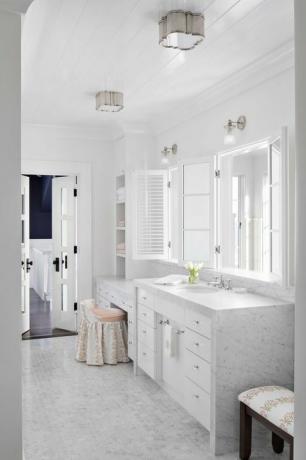 мраморна баня, мраморни плотове, малки мраморни шестоъгълни плочки, бели шкафове, бяло огледало, седалка и табуретка