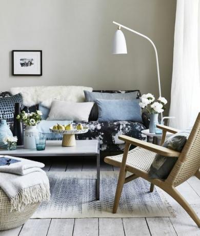 дневна с възглавници на синия шарен диван, бяла подова лампа, наведена над дивана, стъпала, петна и изпъкнали шарки за експресионизъм