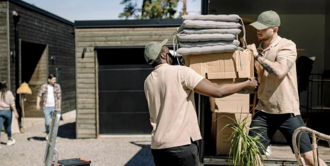 доставчици, които събират картонени кутии от камион през слънчев ден