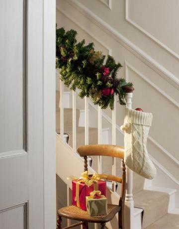 Коледни подаръци и чорапи близо до стълбище в коридора