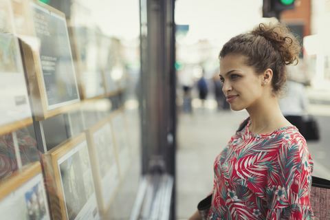 Млада жена разглежда сайтове за недвижими имоти в градската витрина