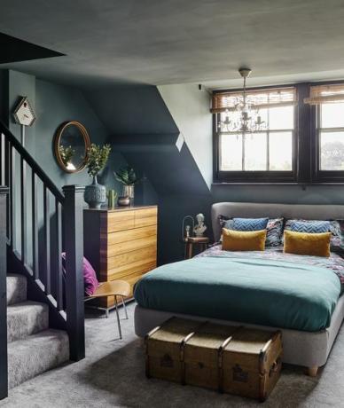 тъмно синя сива таванска спалня с полилей и тапицирано легло