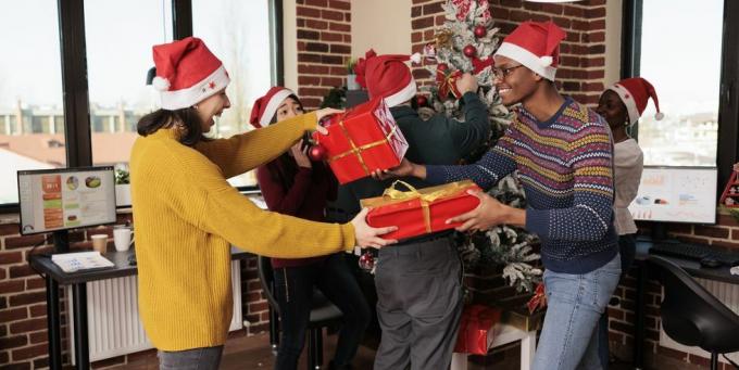 разнообразна група от колеги, които си разменят празнични подаръци