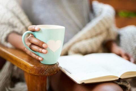 Изрязан кадър на жена, отпускаща се с книга и чаша кафе