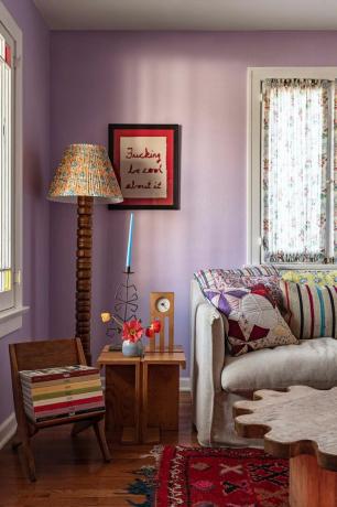 лилав хол с дървена стояща лампа и мебели