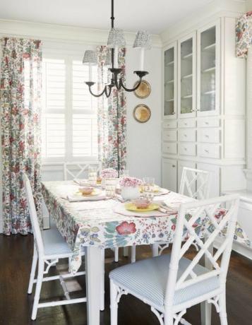 зала за закуска, бели столове за хранене, бели и сини оголени възглавници за столове, бяло съхранение, флорални завеси и плот за маса