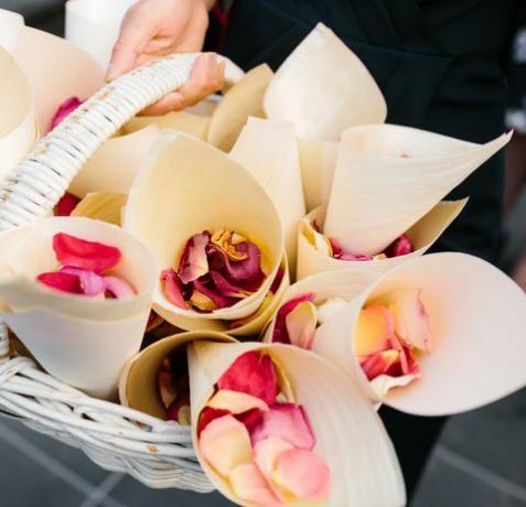 отблизо изображение на розови листенца в бели шишарки, седнали в кошница, които да се използват като конфети на сватбена церемония